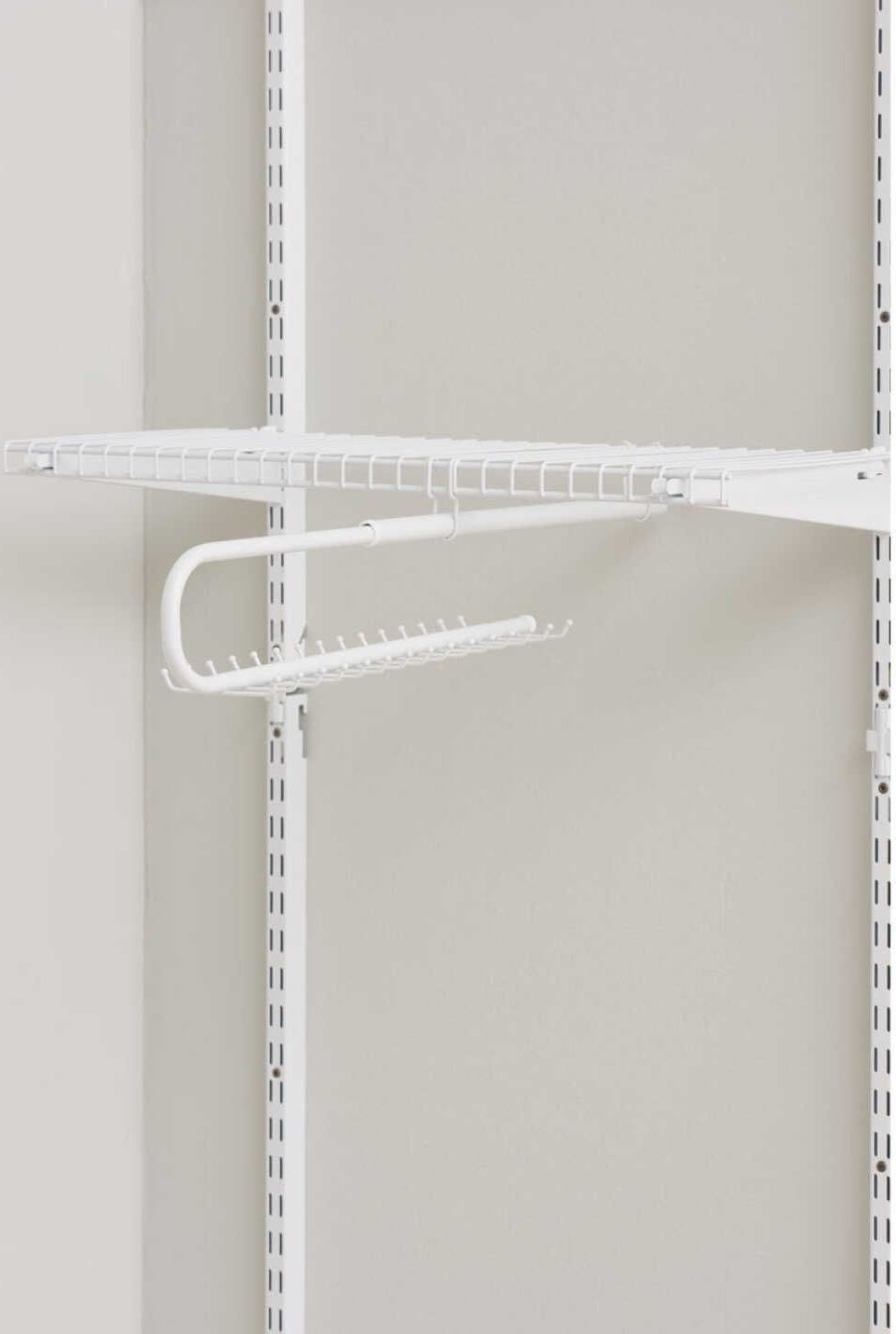 White metal tie and belt organizer attached to adjustable wire shelving in closet organization setting