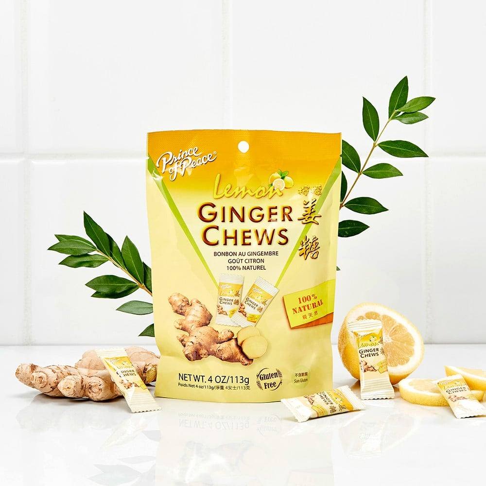 Yellow package of lemon ginger chews surrounded by fresh ginger root and lemon slices in Candy collection under $25