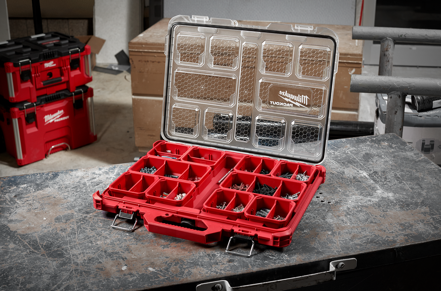 Red low-profile organizer with clear lid and compartmentalized storage for screws and small tool parts in workshop setting
