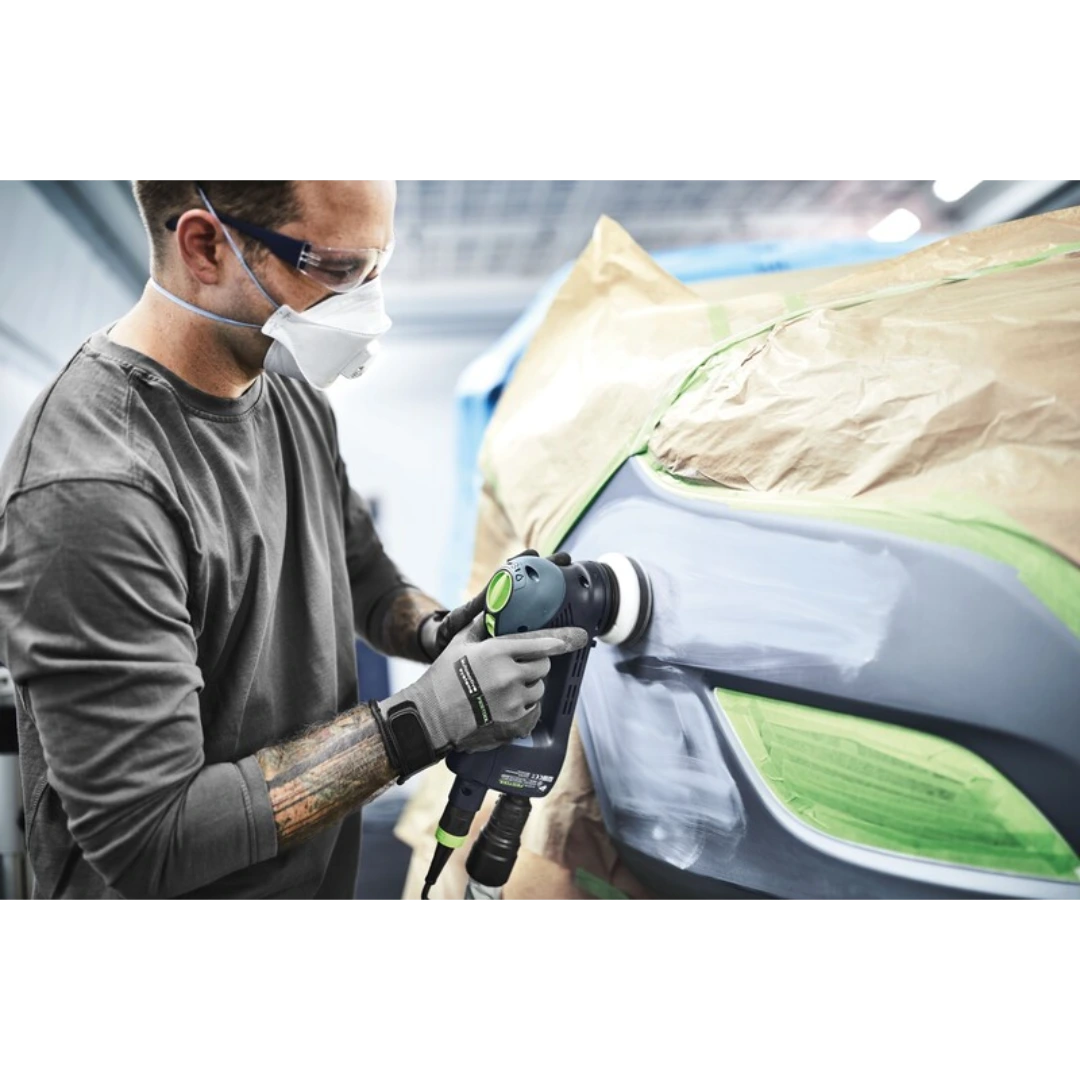 Person wearing protective mask and gloves using a power sander with an interface pad on a taped car surface