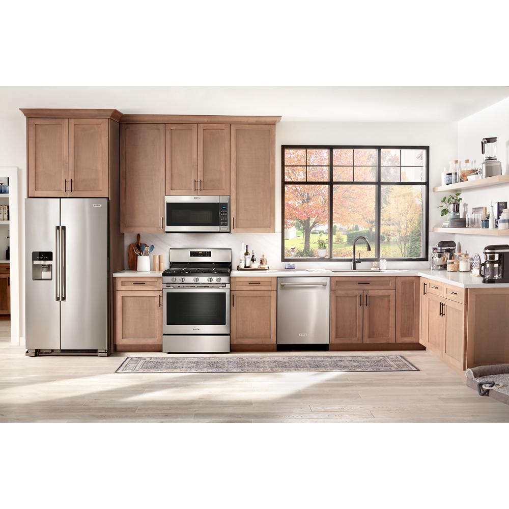 Modern kitchen with stainless steel refrigerator, stove, dishwasher, and over-the-range microwave in wood cabinetry setting