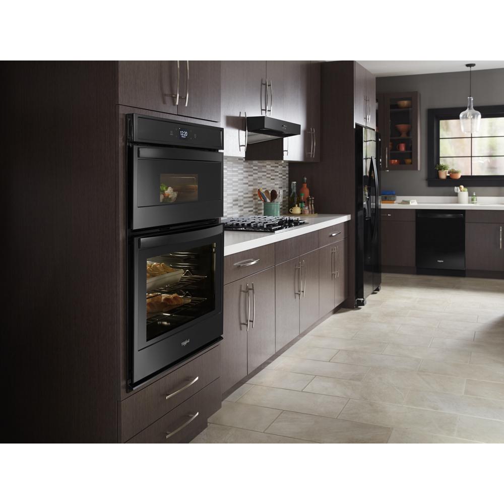 Modern kitchen with built-in black double oven, gas cooktop, and dark wood cabinets in home improvement setting