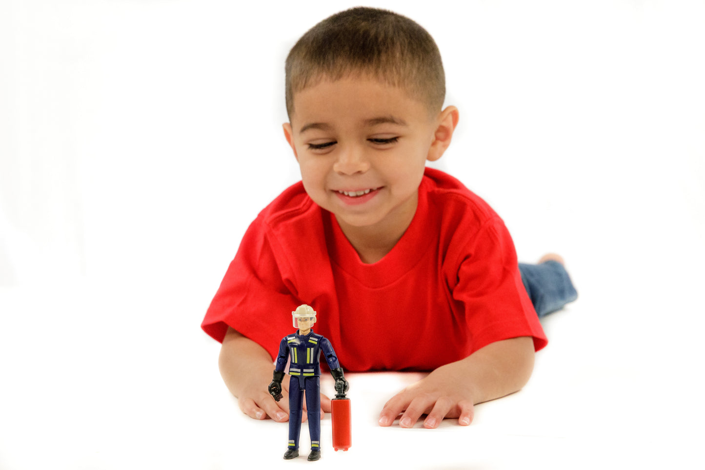 Young boy lying down playing with 1:16 scale firefighter figure holding fire extinguisher in Toys & Games collection