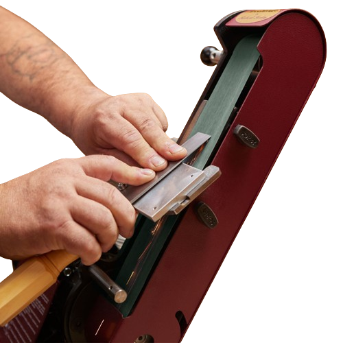 Person sharpening a woodworking blade using a red ProEdge sharpening accessory with manual adjustment controls