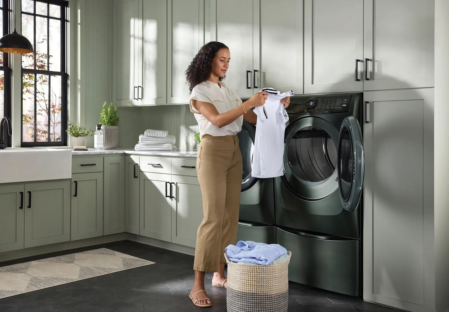 Woman removing white shirt from dark gray front load gas dryer in modern laundry room from Dryers collection