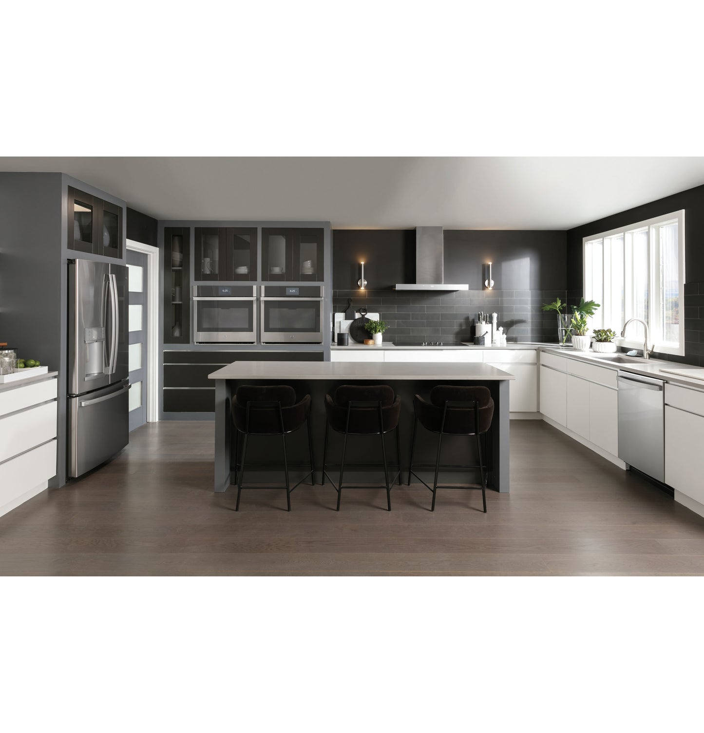 Spacious modern kitchen with dark cabinetry, large island, stainless steel appliances, and designer wall mount vent hood above cooktop