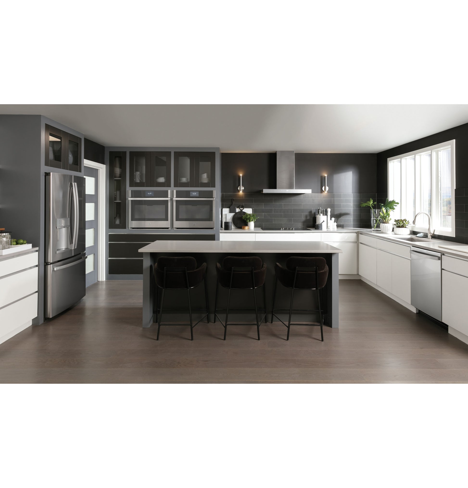 Spacious modern kitchen with dark cabinetry, large island, stainless steel appliances, and designer wall mount vent hood above cooktop