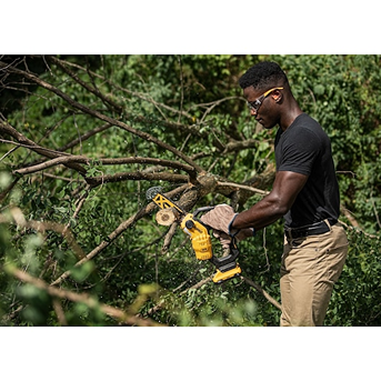 Man cutting tree branches outdoors with a yellow cordless brushless pruning chainsaw for home improvement tasks