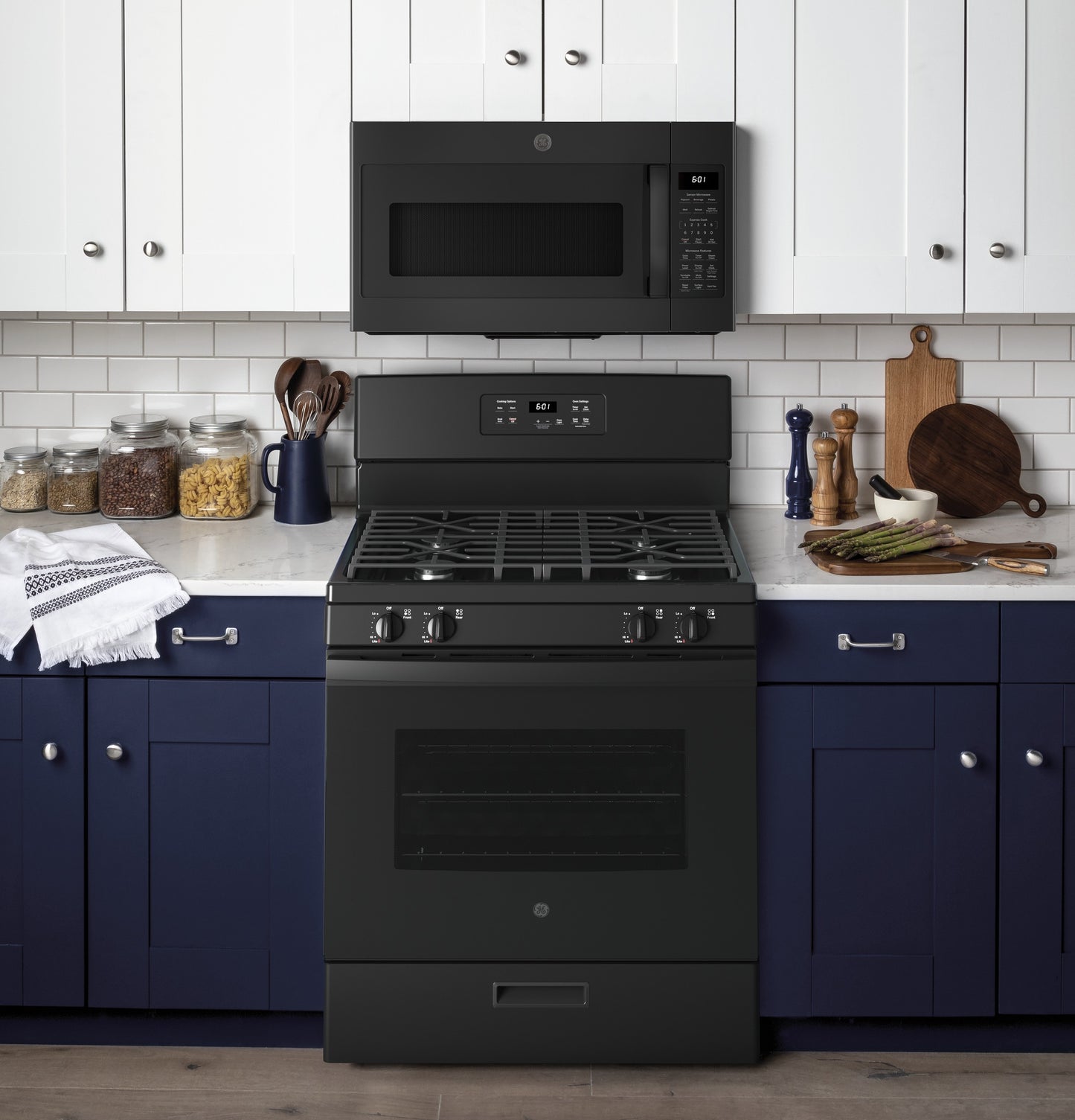 Matte black free-standing gas range with oven and digital display, set in modern kitchen with navy lower cabinets and white upper cabinets