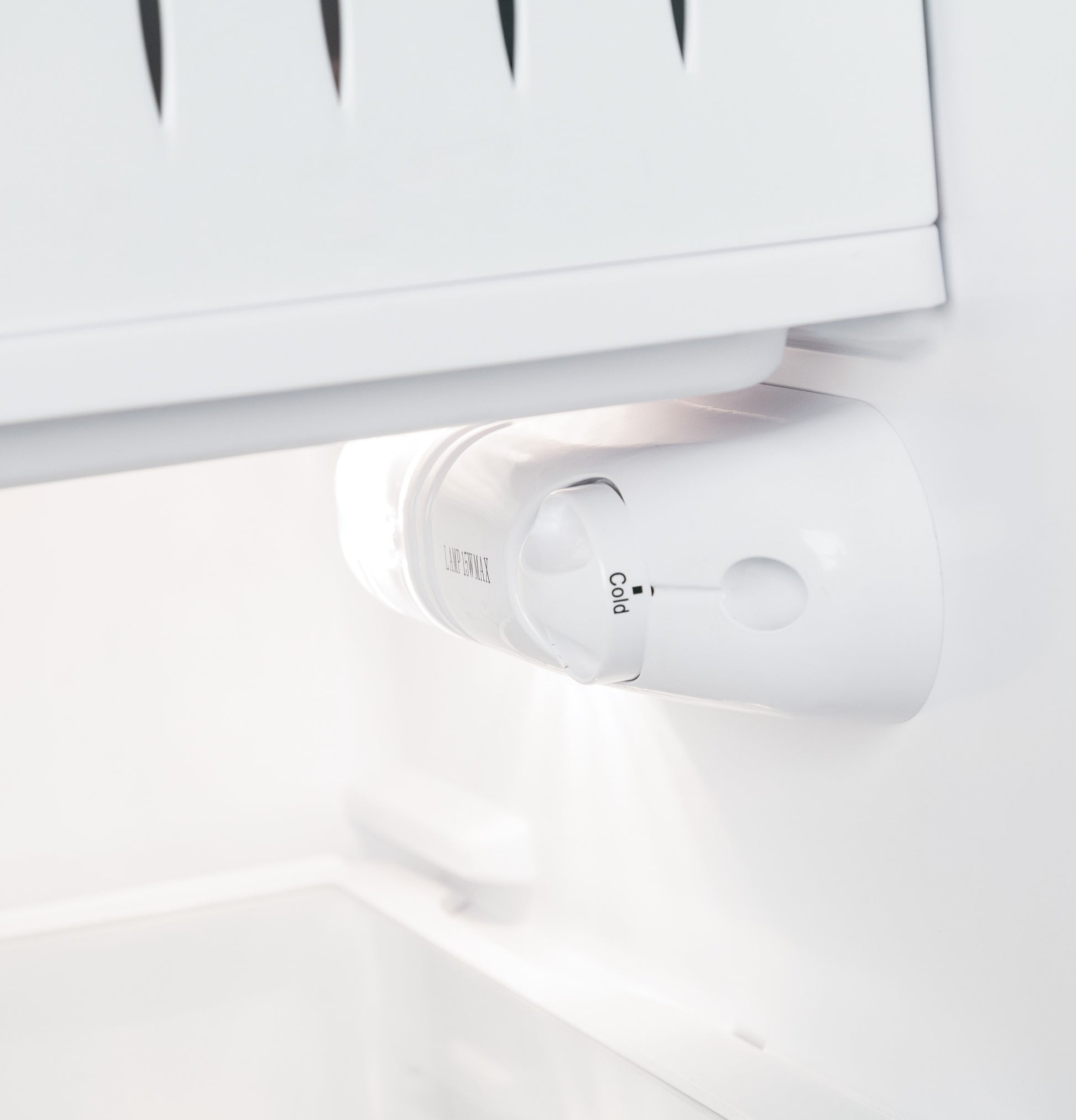 Close-up of white temperature control dial inside compact refrigerator in mini refrigerators and kitchen appliances collection
