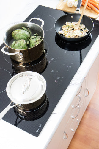 Black induction cooktop with five cooking zones in a modern kitchen for home improvement and kitchenware use