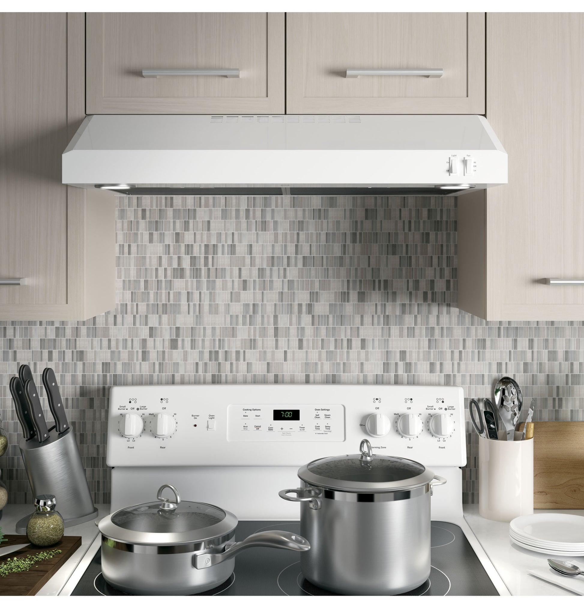 White ENERGY STAR certified under cabinet range hood installed above white stove with cookware in modern kitchen setup