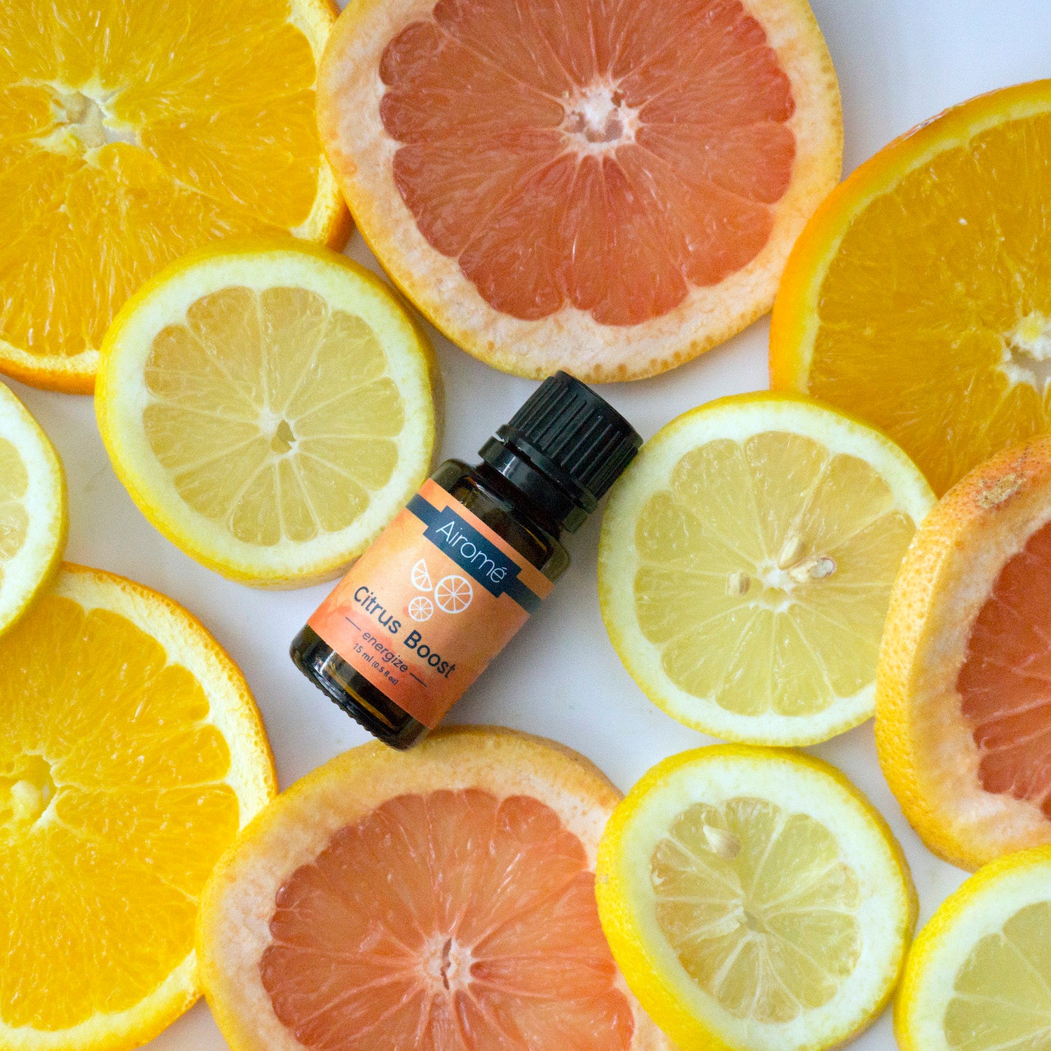 Small amber essential oil bottle labeled Citrus Boost surrounded by fresh citrus fruit slices including orange and grapefruit