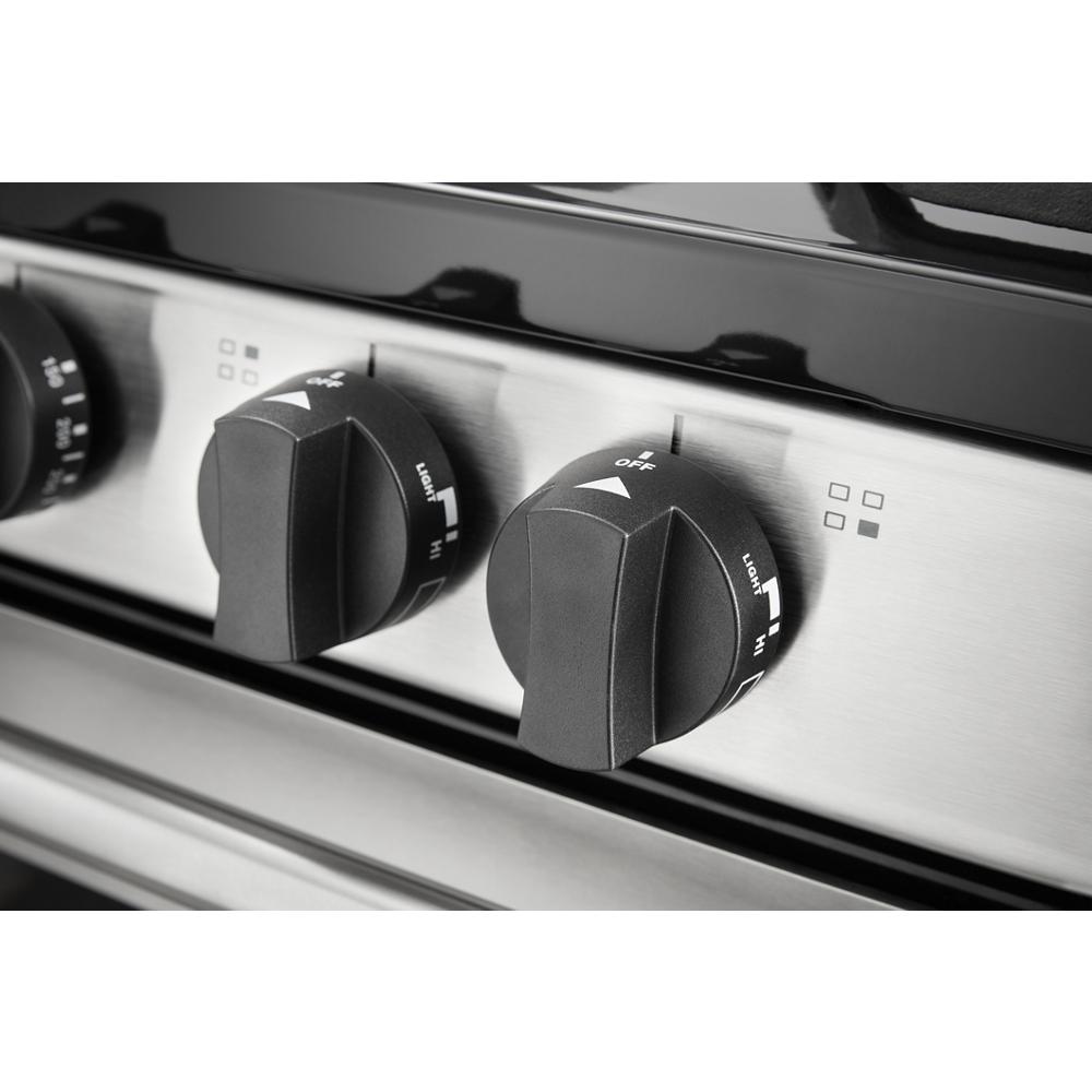 Close-up of black burner control knobs on stainless steel panel of a freestanding gas range for kitchen improvement
