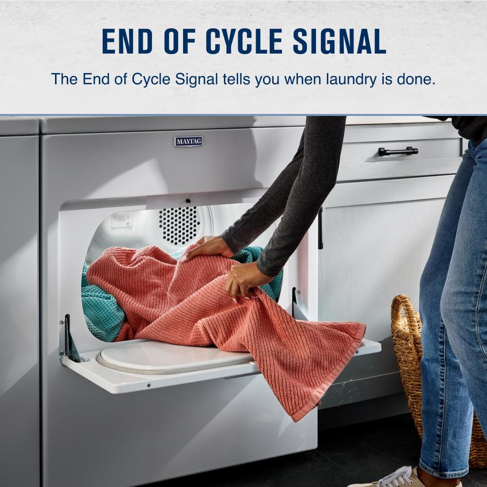 Person removing coral and teal blankets from a white top load electric dryer in a modern laundry setting