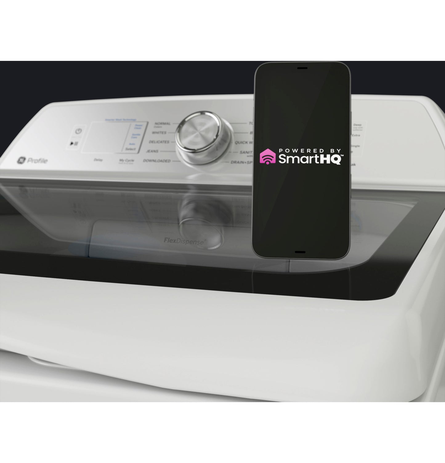 Close-up of white top load washer control panel with rotary dial and smartphone displaying SmartHQ app for remote control.