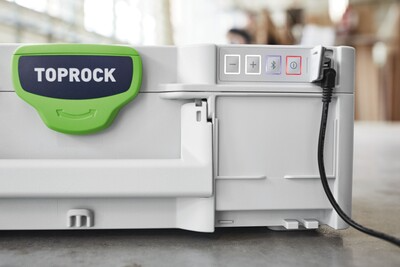 Close-up of a gray and green Festool TOPROCK Bluetooth speaker case connected with a power cable in a workshop setting