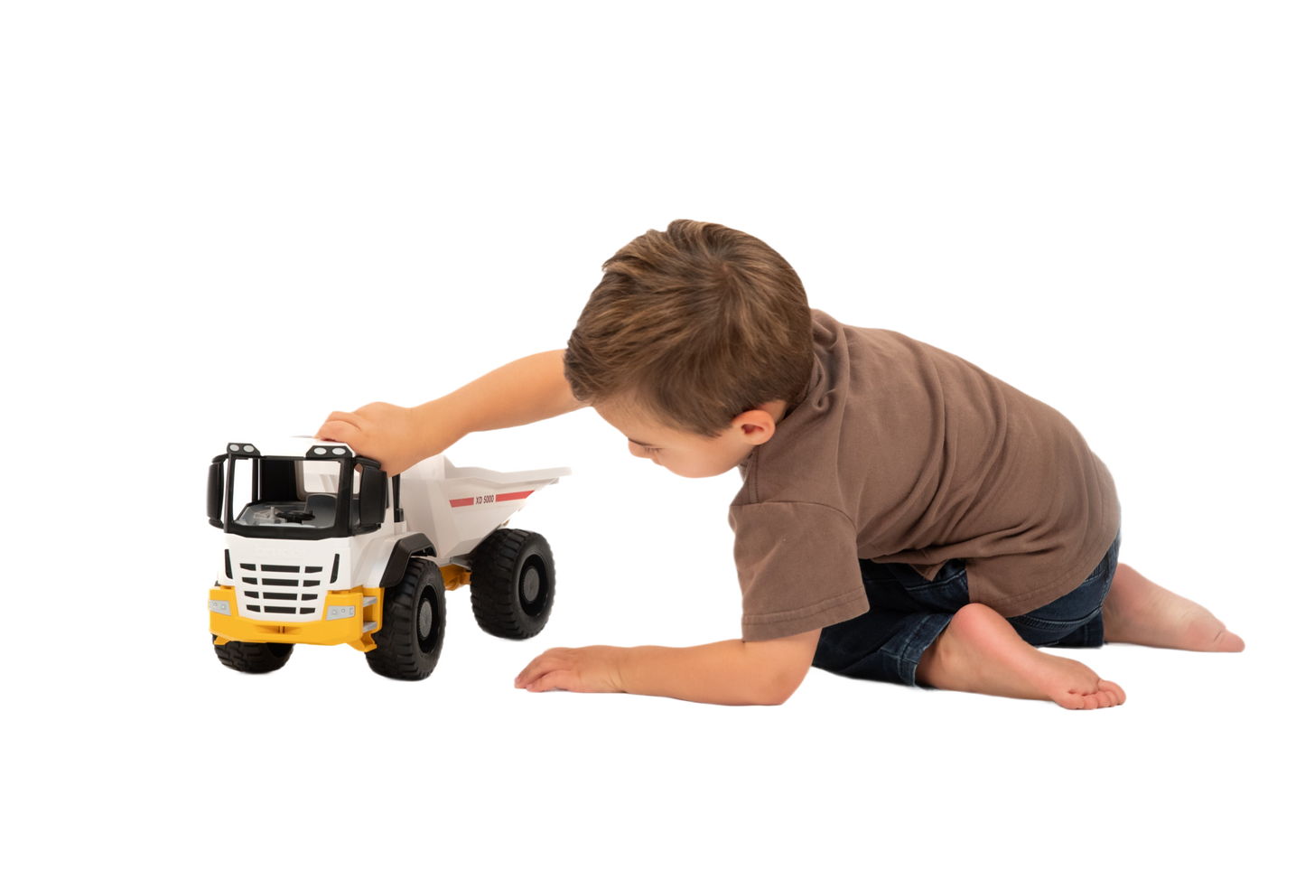 Child playing with a white and yellow Bruder toy dump truck from Vehicles & Remote Controlled Toys collection under $100