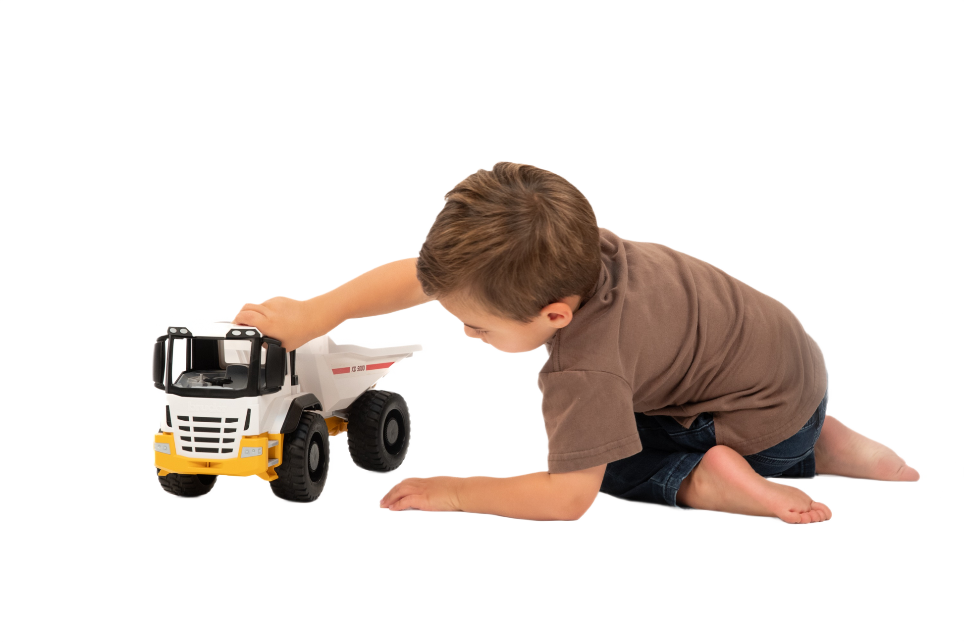 Child playing with a white and yellow Bruder toy dump truck from Vehicles & Remote Controlled Toys collection under $100