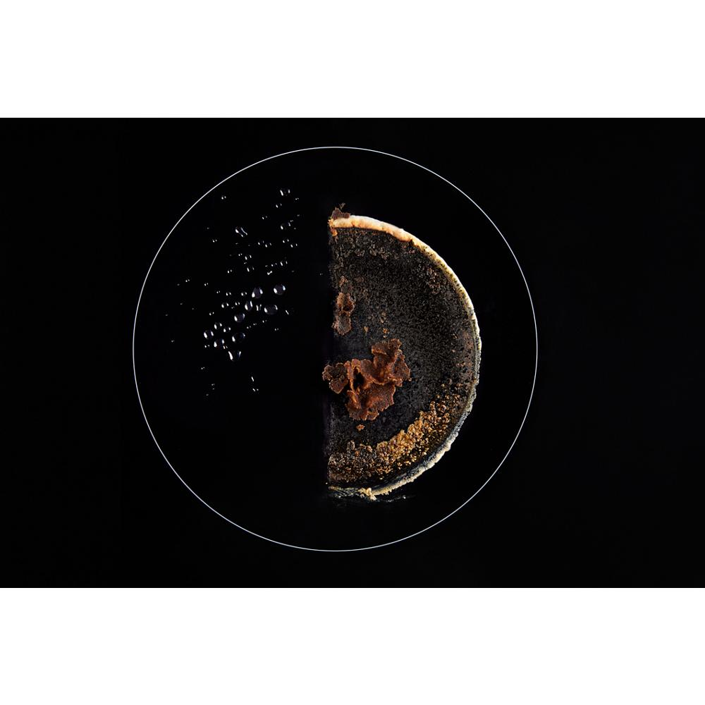 Close-up of burnt food residue and crumbs on a black induction cooktop surface circular cooking zone