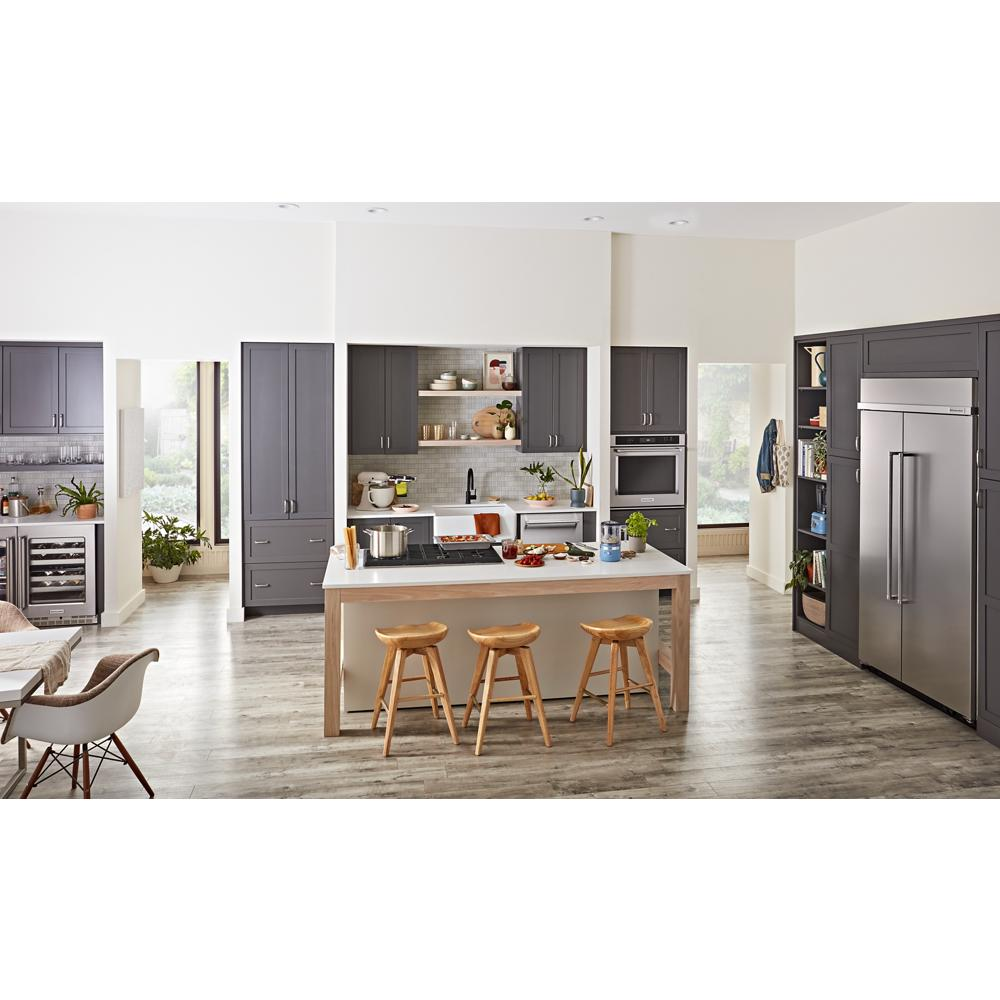 Spacious modern kitchen with gray cabinetry, central island with wooden stools, and stainless steel appliances in KitchenAid collection