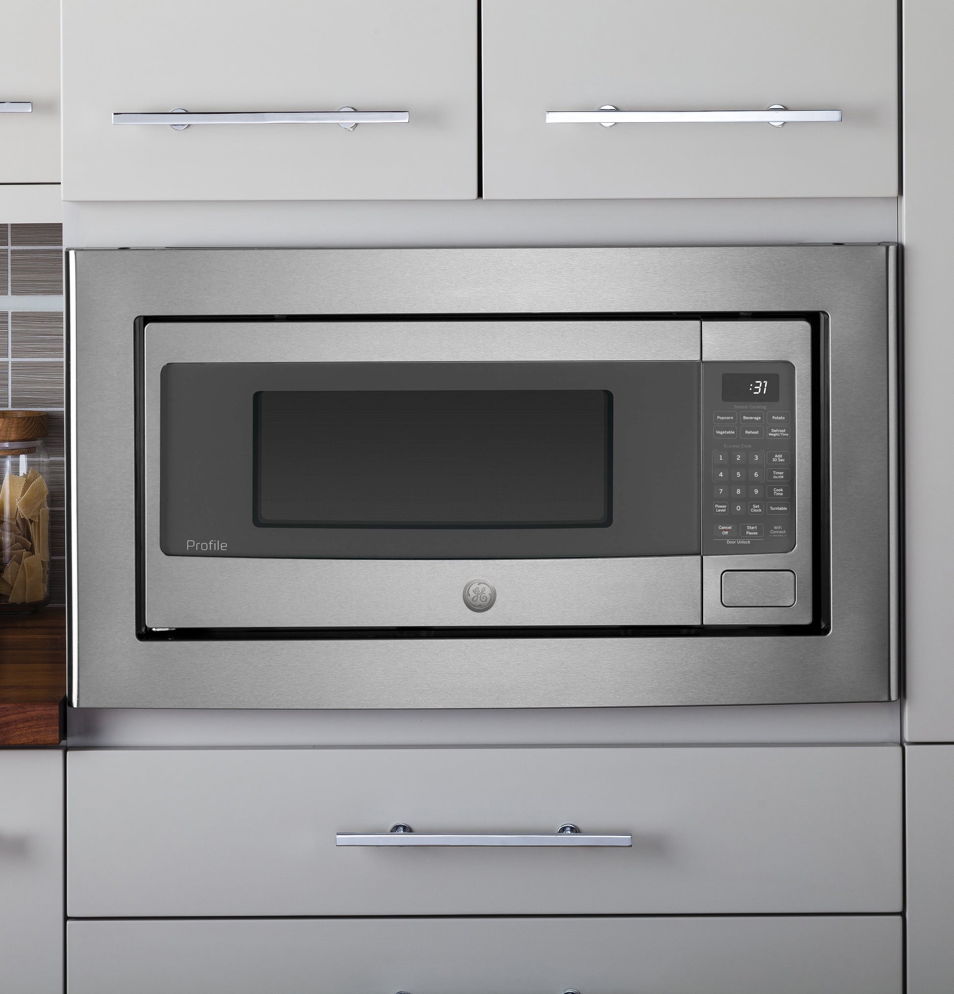Built-in stainless steel microwave oven with digital control panel integrated into gray kitchen cabinetry from appliances collection