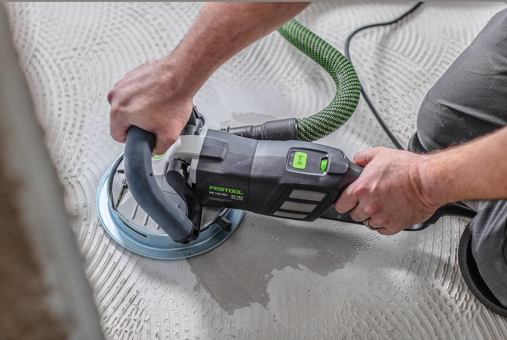 Person using a Festool diamond grinder on a floor surface, connected to a dust extraction hose in a home improvement setting