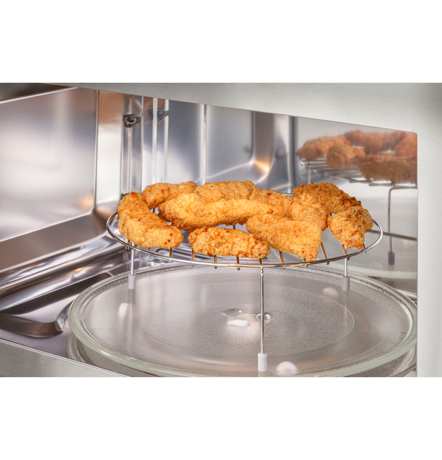 Over-the-range convection microwave oven interior with crispy breaded chicken tenders on raised cooking rack
