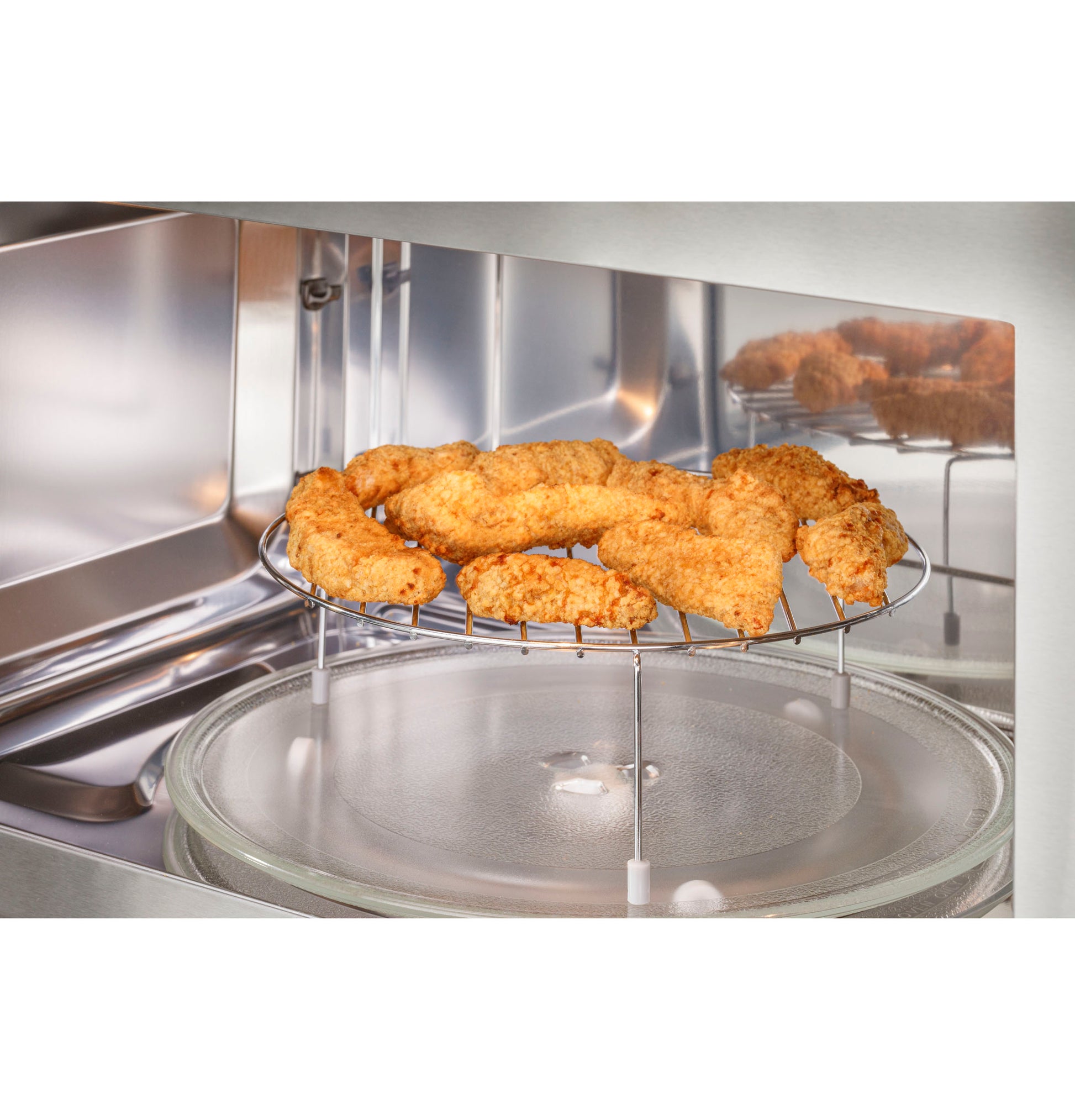Over-the-range convection microwave oven interior with crispy breaded chicken tenders on raised cooking rack