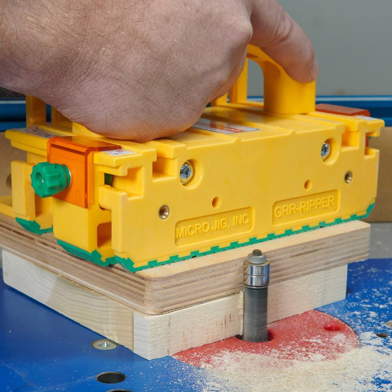 Yellow Microjig tool with safety grip guiding wood over router bit in saw accessories and power tool collections