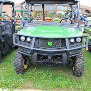 Green utility vehicle with brush guard, rugged tires, and protective roof suitable for tools and home improvement use
