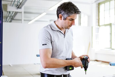 Man using a compact cordless drill for precision home improvement tasks in a bright workspace
