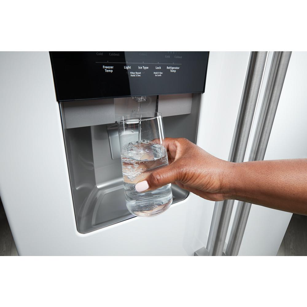 Hand filling glass with water from dispenser on stainless steel side-by-side refrigerator in Appliances collection