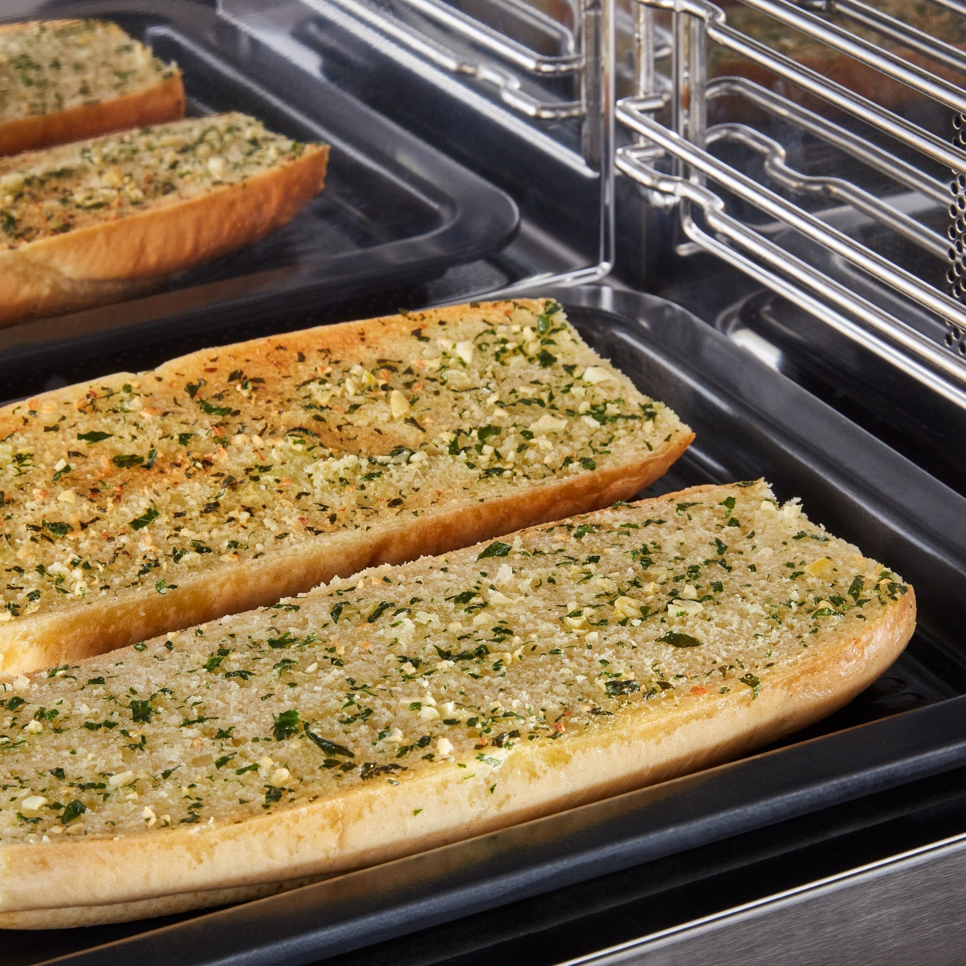 Garlic bread toasting inside multifunction over-the-range oven with flush built-in stainless steel design