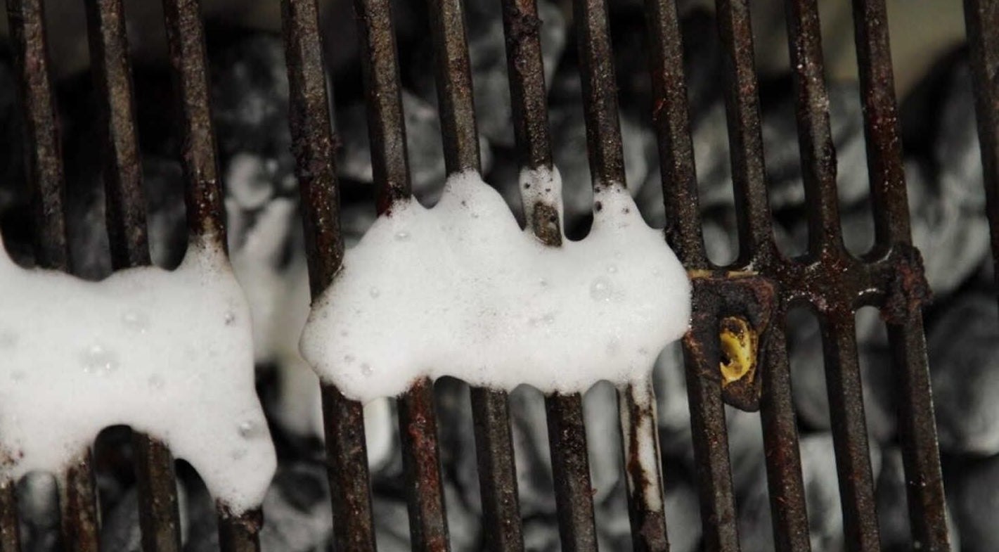 Foaming cleaner applied to rusty grill grate for removing grease and grime in home improvement tasks