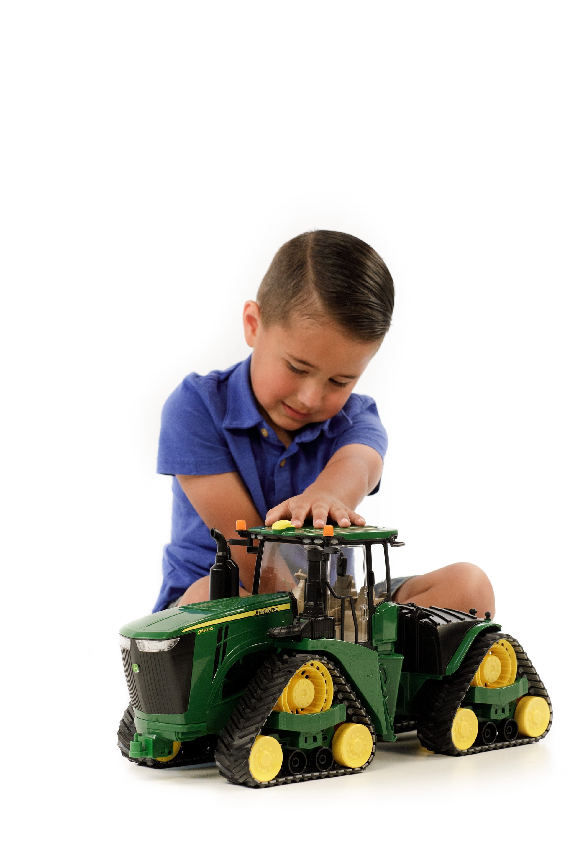 Young boy playing with green and yellow Bruder toy tractor from Vehicles & Remote Controlled Toys collection