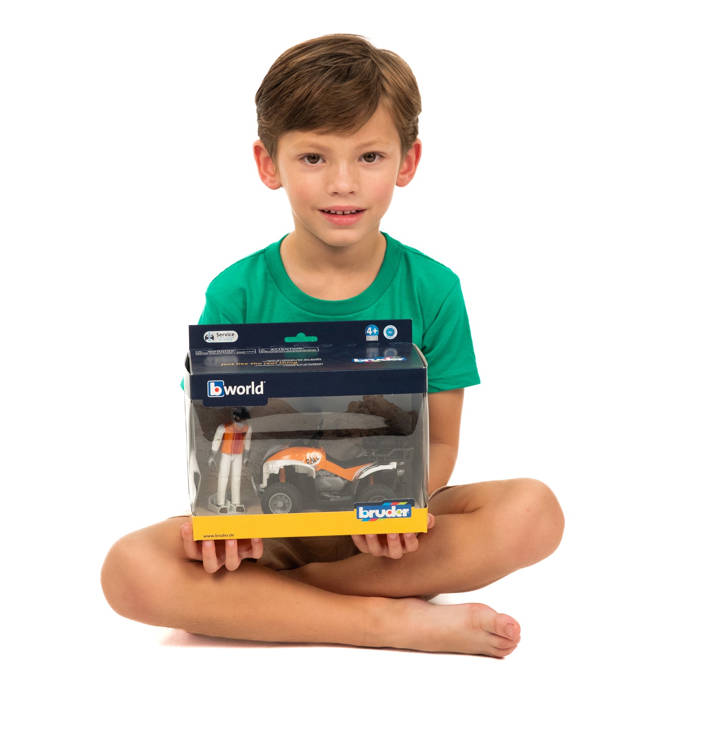 Young boy sitting cross-legged holding boxed Bruder Quad Bike with Driver toy from Toys & Games collection