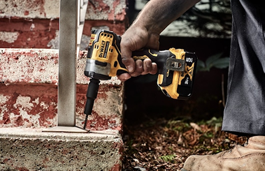 Cordless impact wrench in black and yellow tightening bolts on metal post for tools and home improvement projects