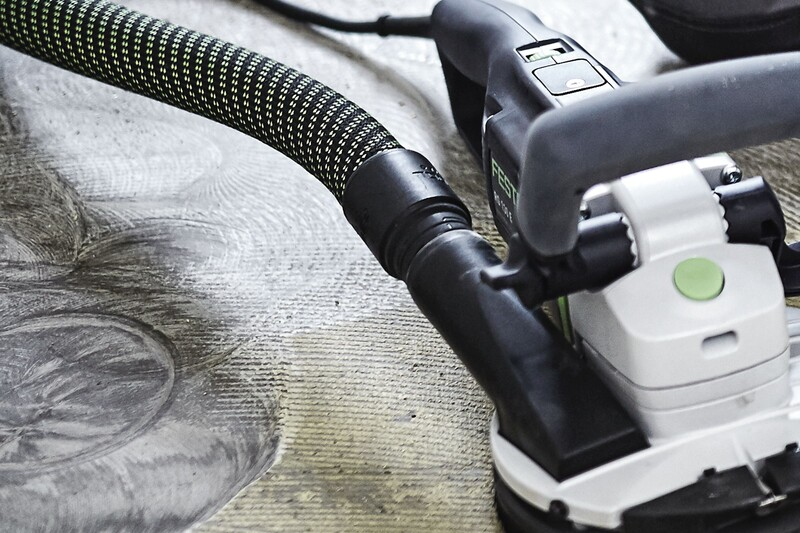 Black and green braided extractor hose connected to a power sanding tool for home improvement and woodworking tasks
