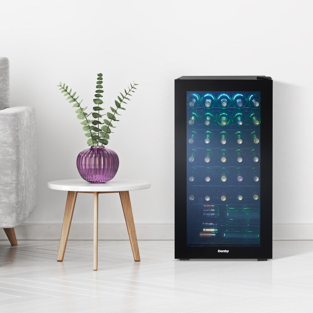 Free-standing 36 bottle wine cooler with black frame, blue LED interior lighting, and wire shelving in modern kitchen setting
