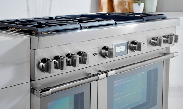Stainless steel dual fuel range with control knobs, digital display, and large oven doors in modern kitchen setting