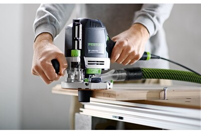 Hands operating a Festool router on a wooden board for precise home improvement woodworking tasks with dust extraction