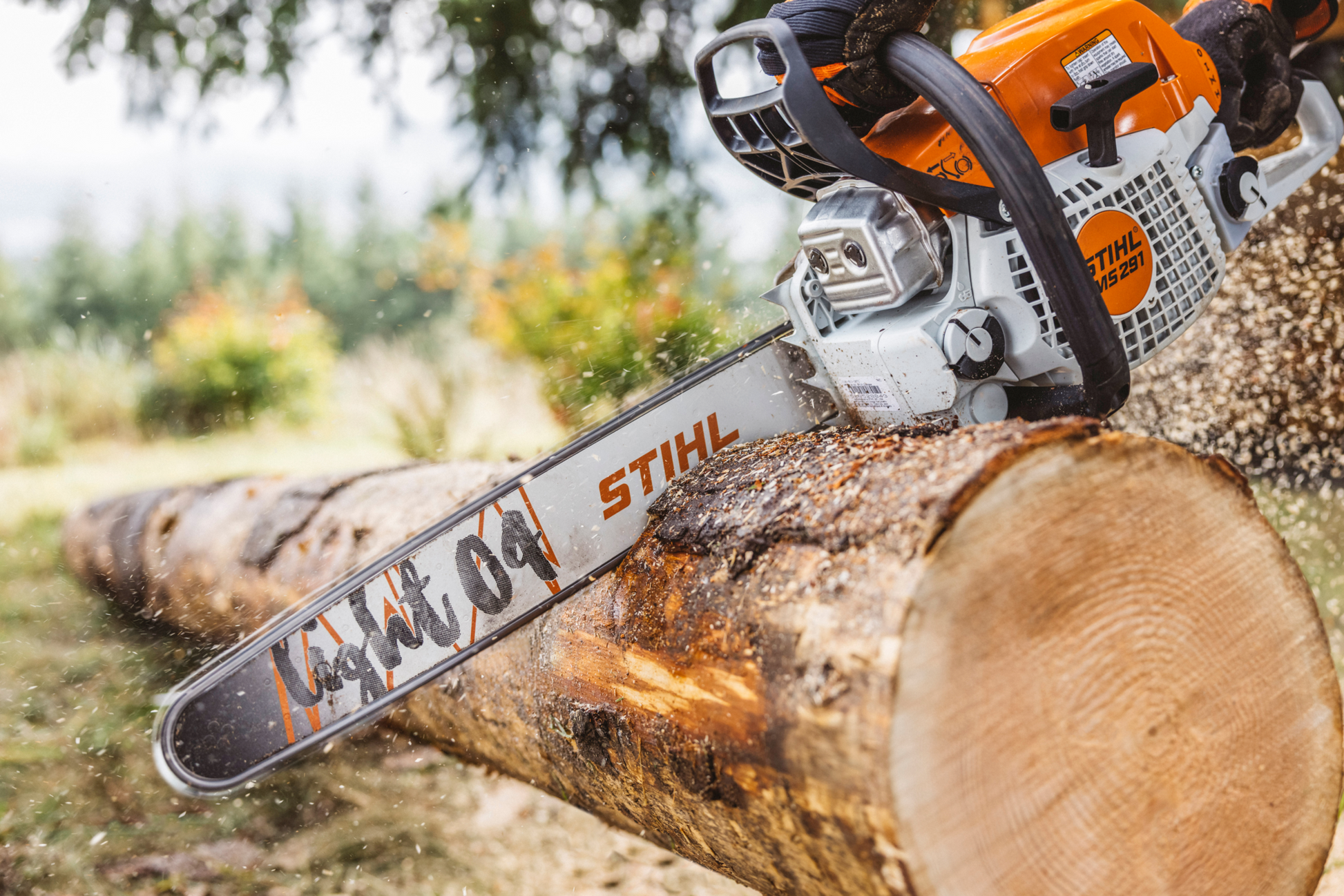 Orange and white STIHL chainsaw efficiently cutting a large log outdoors for tools and home improvement use