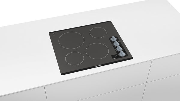 Black glass electric cooktop with four heating zones and control knobs in Bosch appliances and kitchenware collection