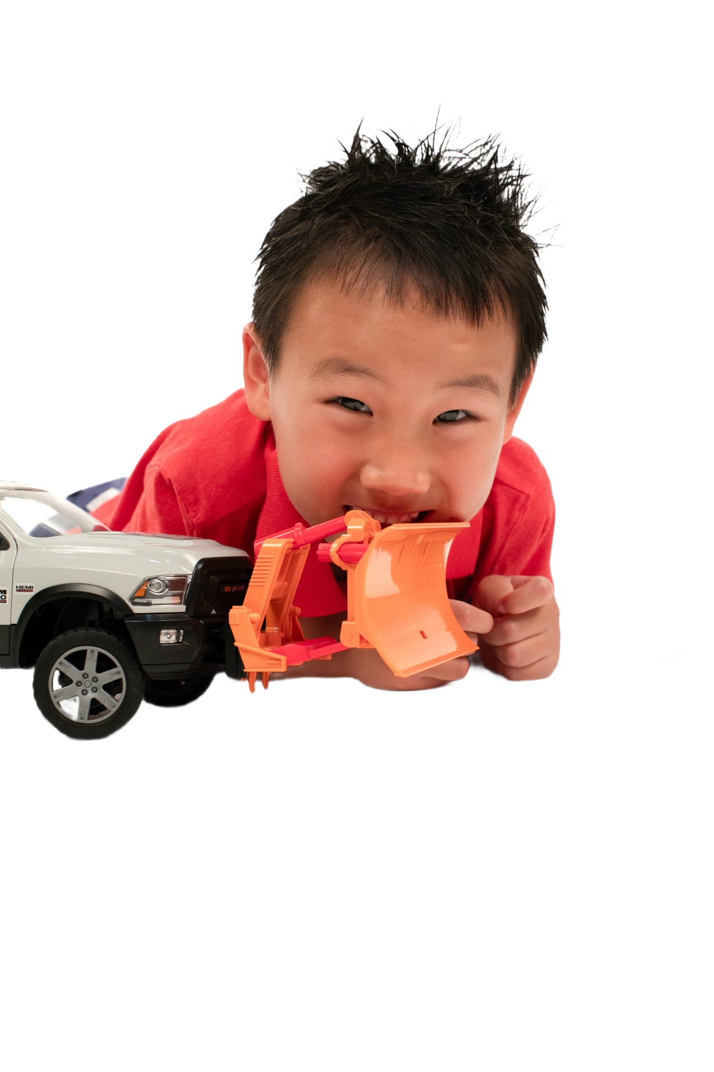 Child playing with white toy truck equipped with an orange Bruder Toys plow blade for imaginative construction play