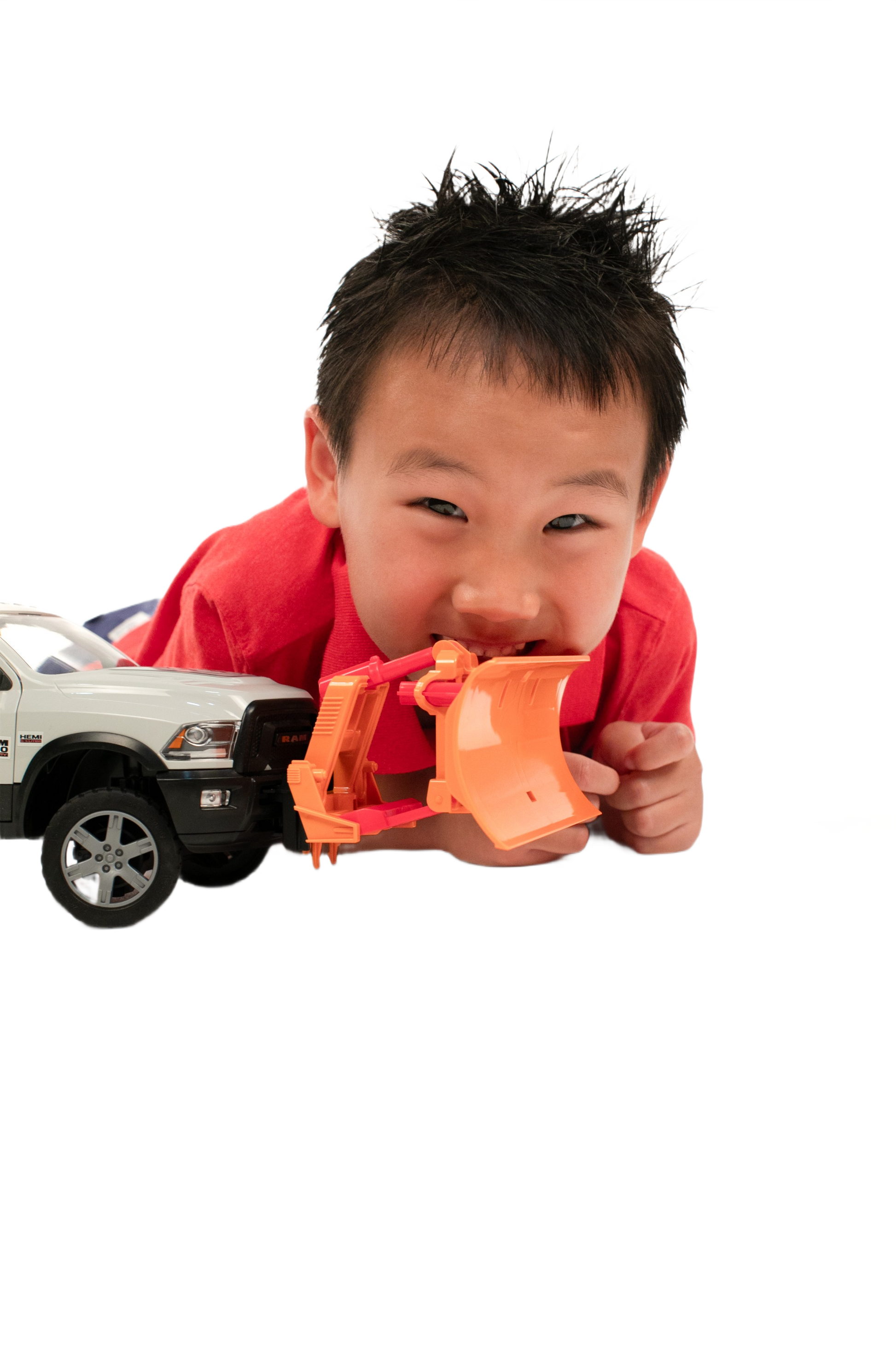 Child playing with white toy truck equipped with an orange Bruder Toys plow blade for imaginative construction play
