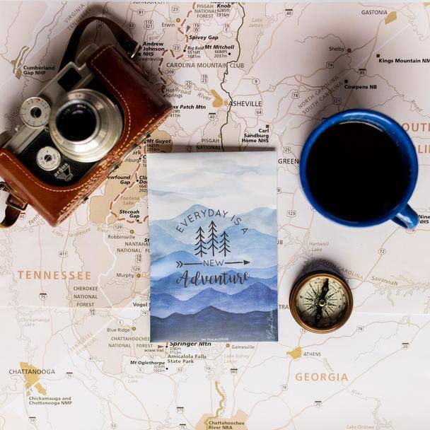 Vintage camera, coffee cup, compass, and adventure-themed card on a detailed travel map for household items collection