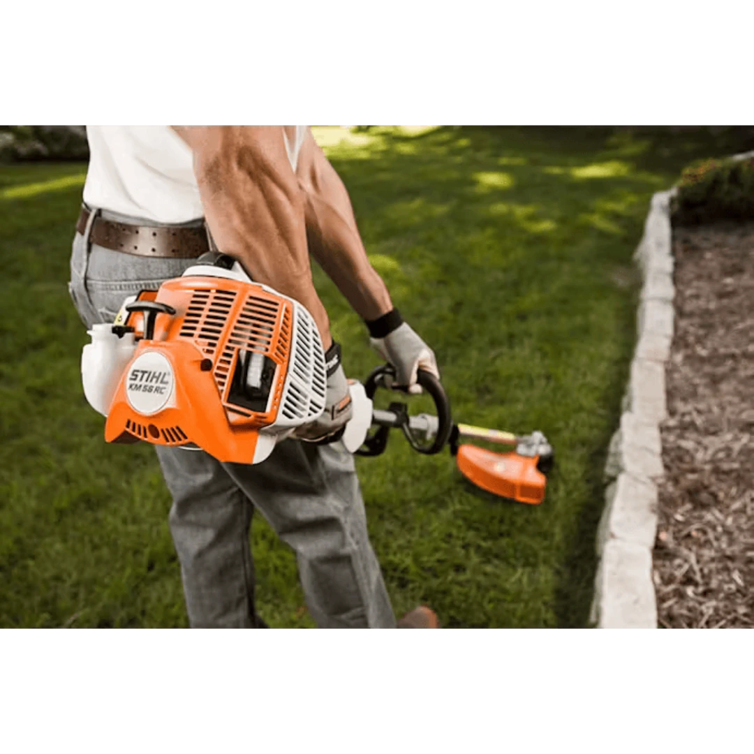 Close-up of person operating orange and white KombiMotor trimmer for garden edging along lawn border