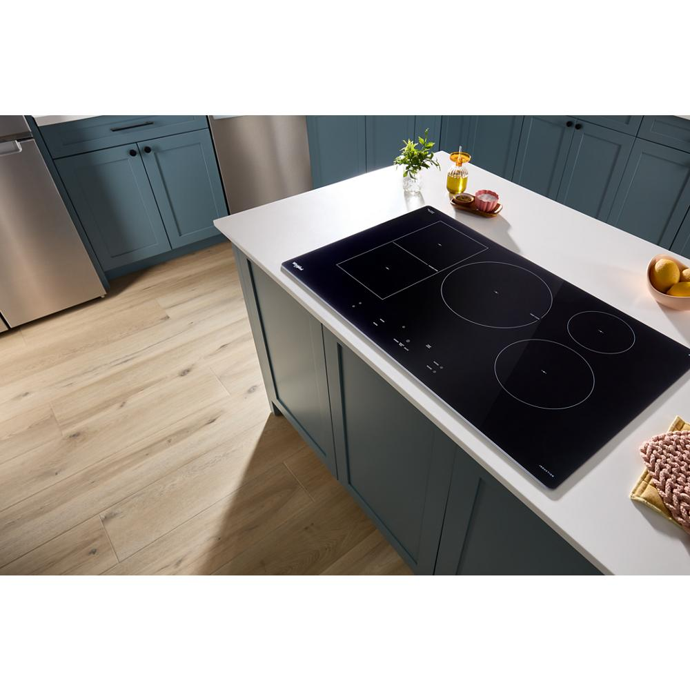 Black glass induction cooktop with three cooking zones and touch controls installed in a modern kitchen island setting