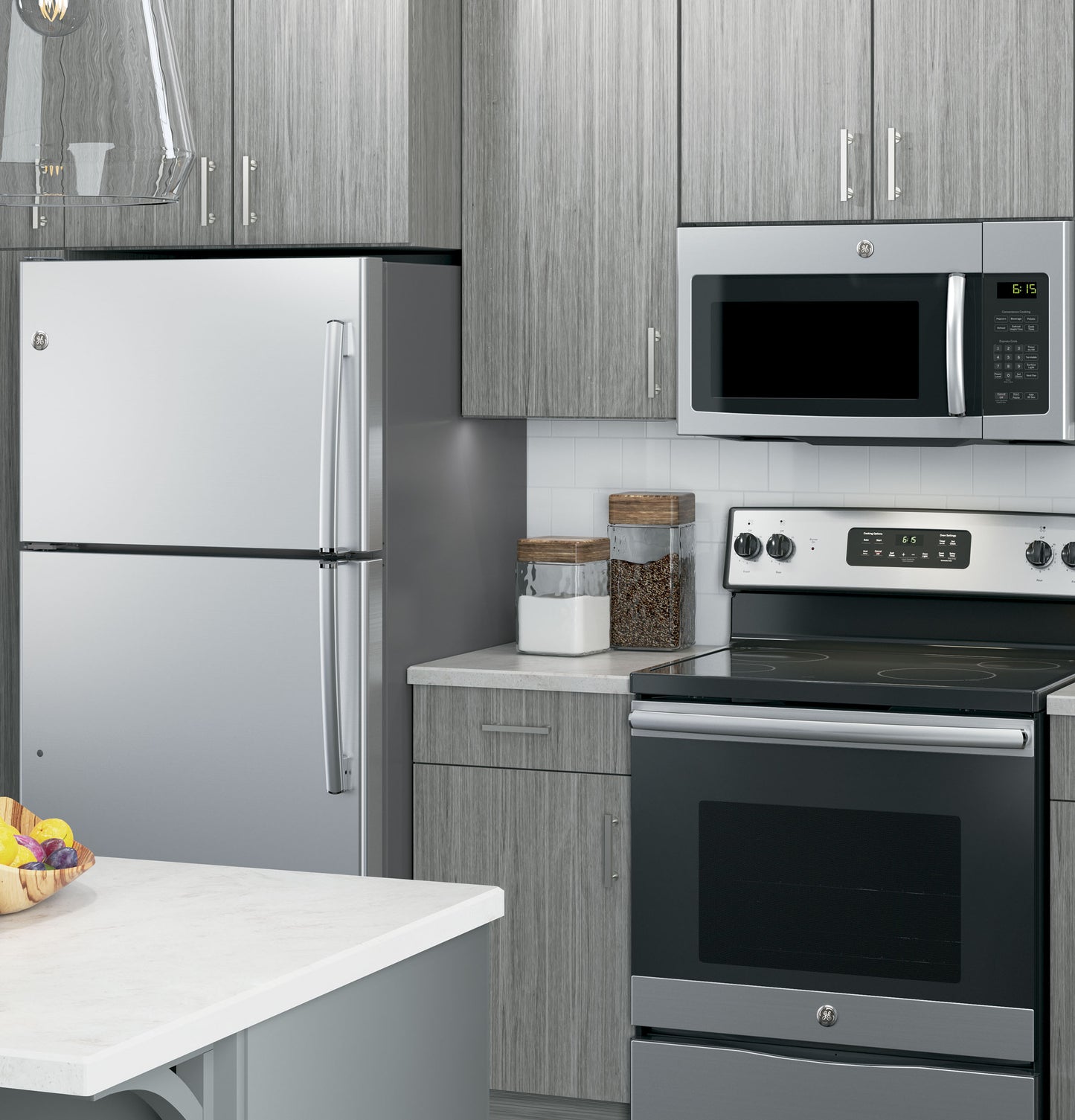 Modern kitchen featuring a stainless steel microwave mounted above a glass electric range with gray wood cabinets